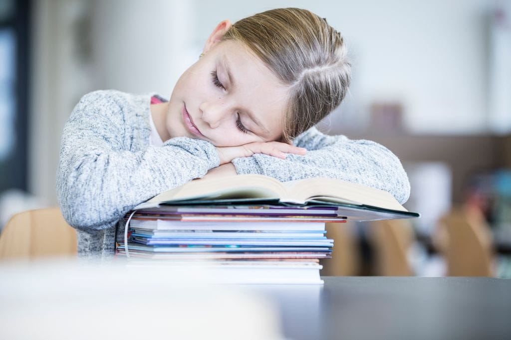 niña dormida en clase, sobre los libros
