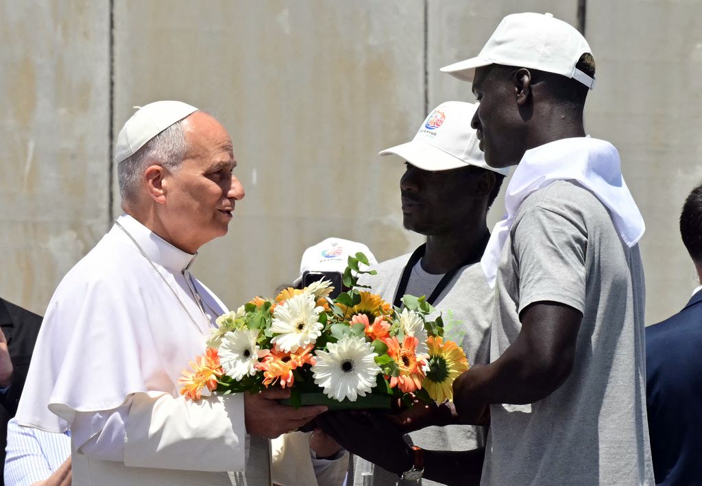 El papa León XIV recibe una corona de flores de manos de dos migrantes para rendir homenaje a todas aquellas personas que perdieron la vida en el mar recibe una corona de flores de manos de dos migrantes para rendir homenaje a todas aquellas personas que perdieron la vida en el mar