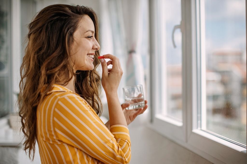 mujer tomando suplementos en casa