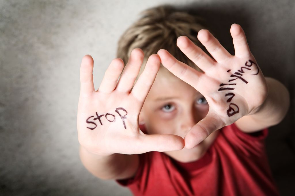 Niño con mensaje pintado en las manos de STOP Bullying