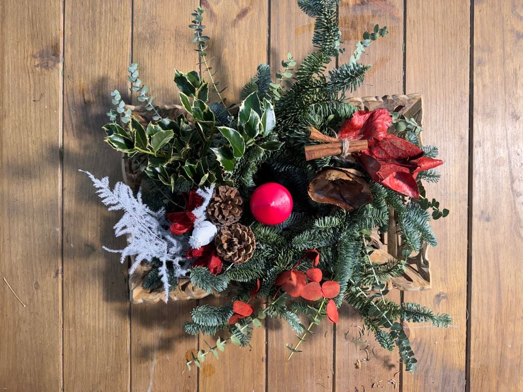 Centro de mesa navideño terminado, con ramas de canela decorando un extremo
