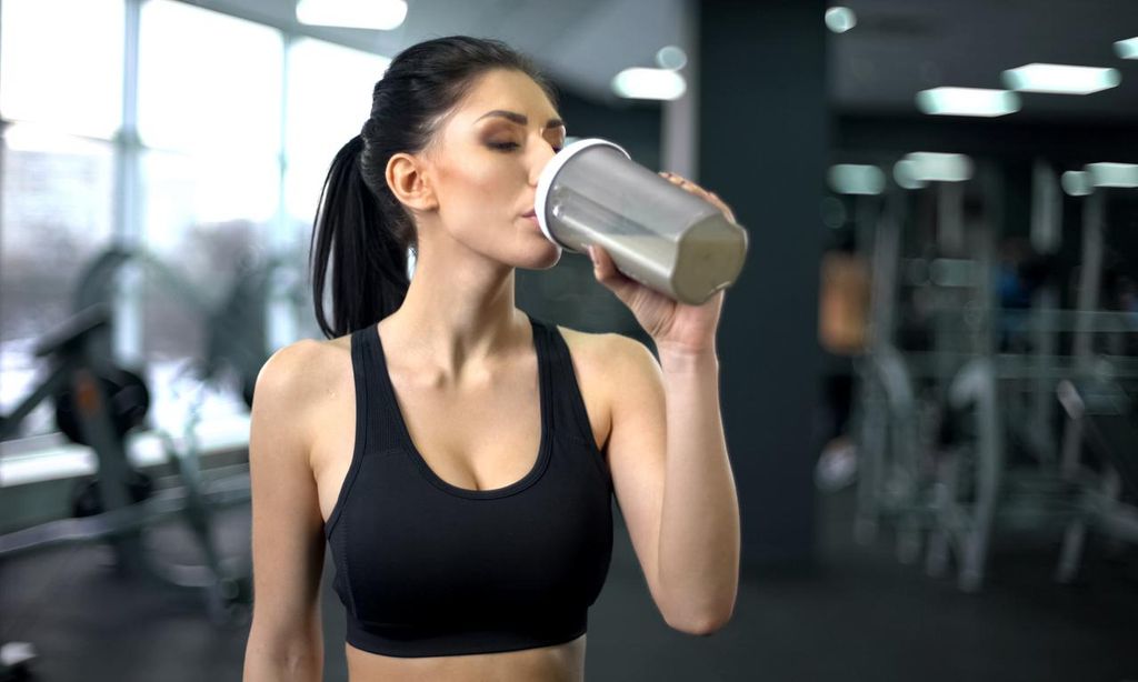 Mujer toma bebida de proteína