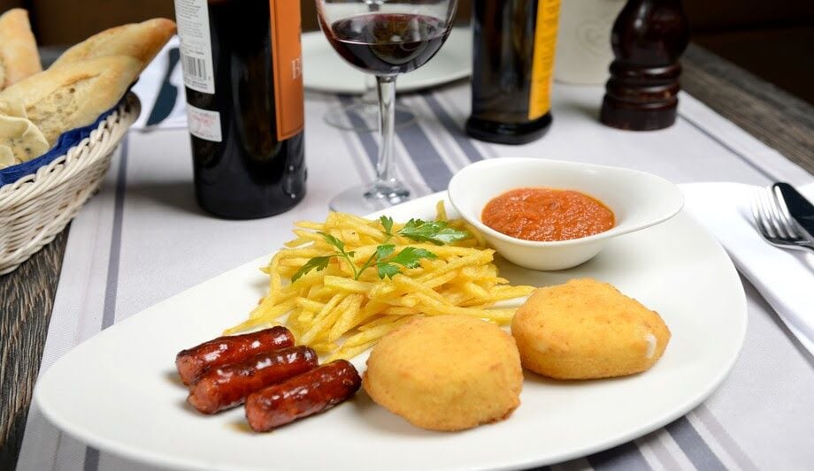 Huevos encapotados con chistorra, patatitas fritas y salsa de tomate.