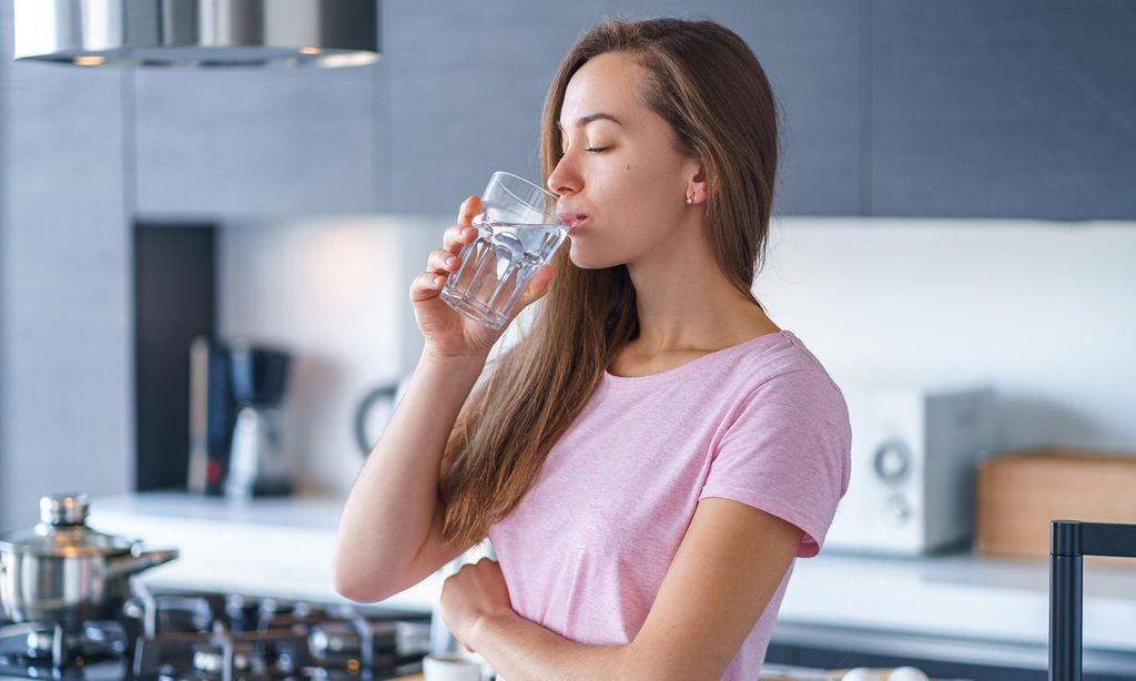 mujer bebiendo agua en la cocina