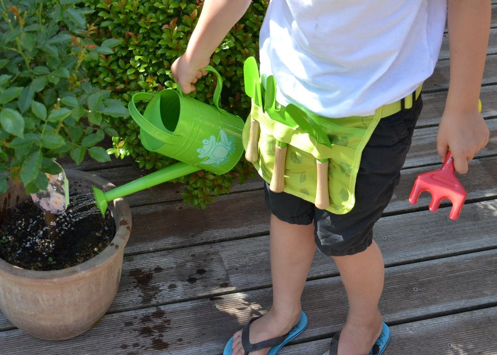 Niño con herramientas de jardinero y una regadera