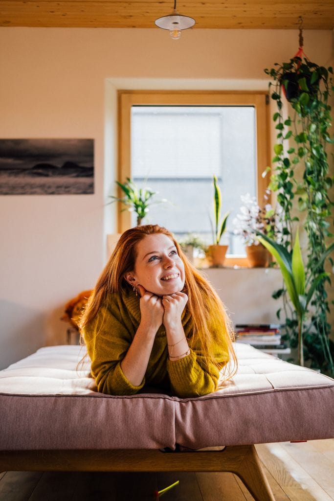 mujer en casa, sonriente, tumbada en el sofá