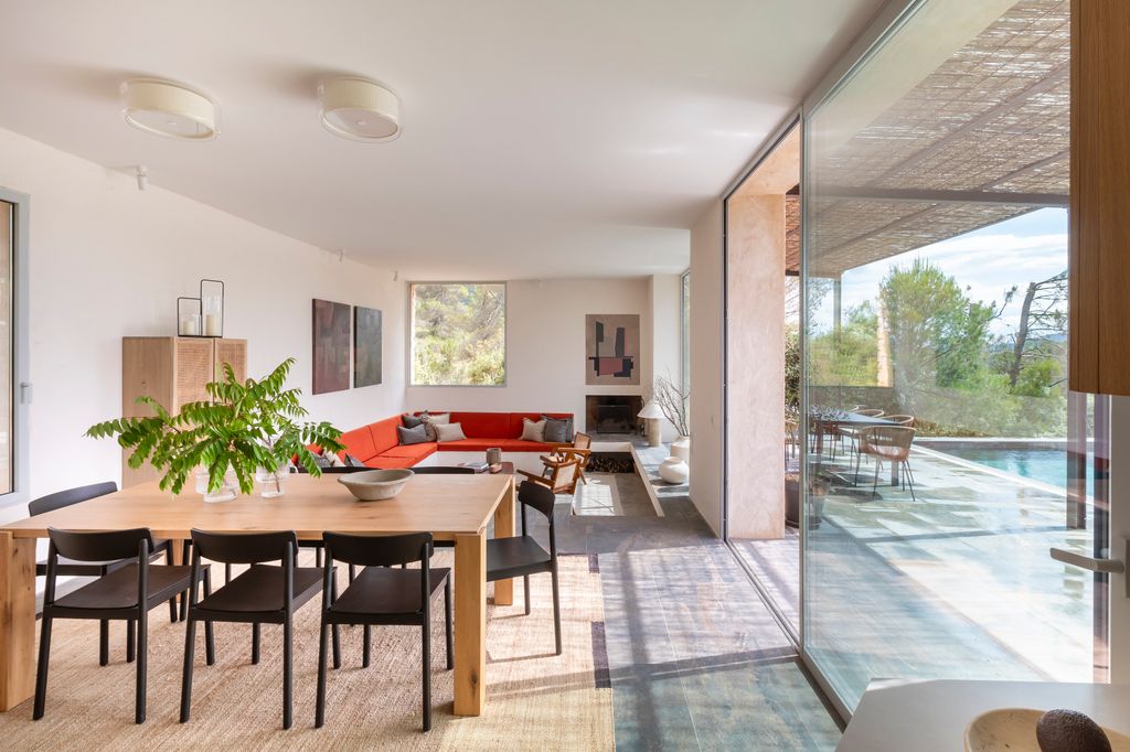 Salón comedor con salida a la piscina, con mesa de madera, sillas negras, sofá rojo, alfombra