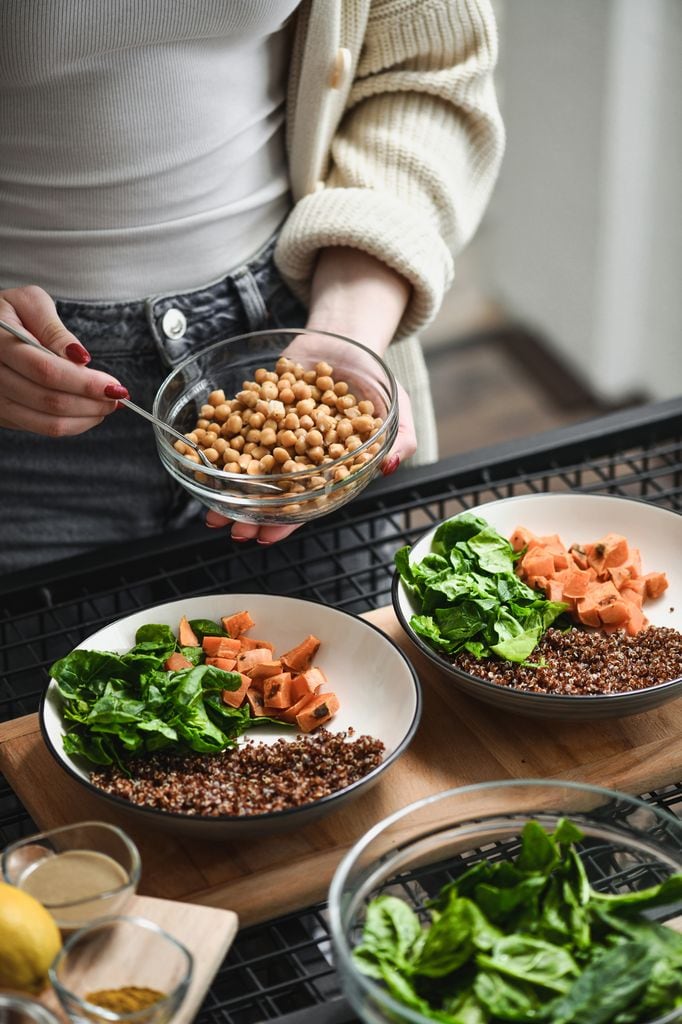 Una mujer preparando un plato combinado con legumbres