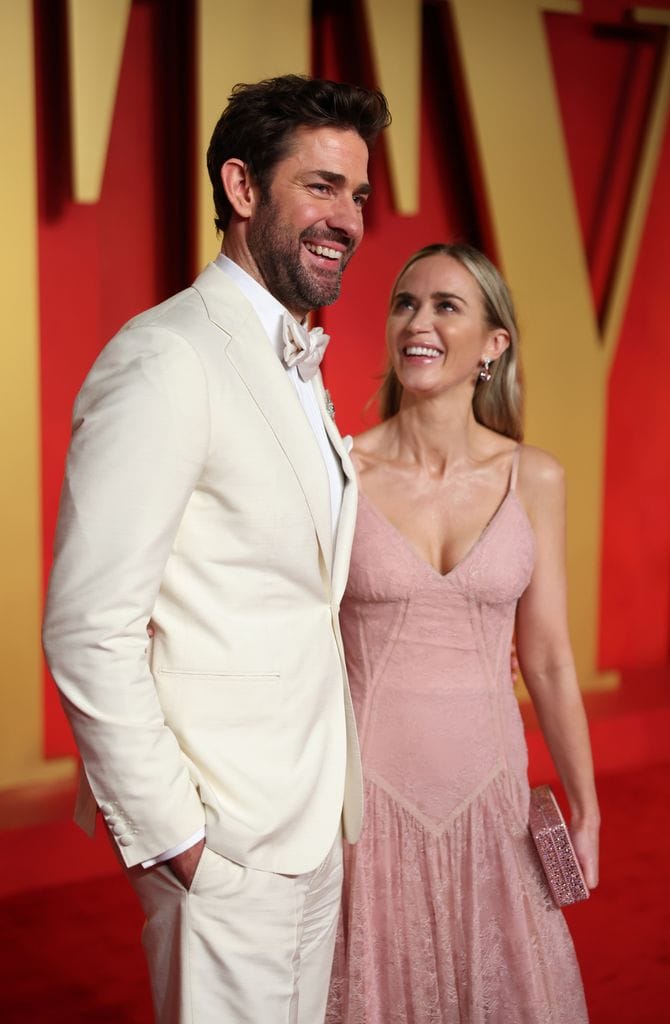 Plano medio de Emily Blunt y John Krasinki con traje blanco y vestido rosa