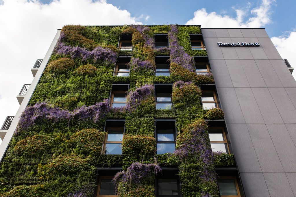 Fachada vegetal con plantas verdes y moradas, una envolvente vida que atrae vida, muy especialmente a especies polinizadoras