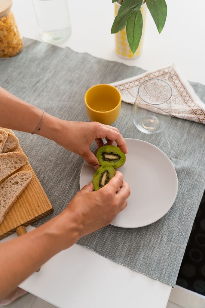 Una mujer colocando un kiwi partido en dos en un palto