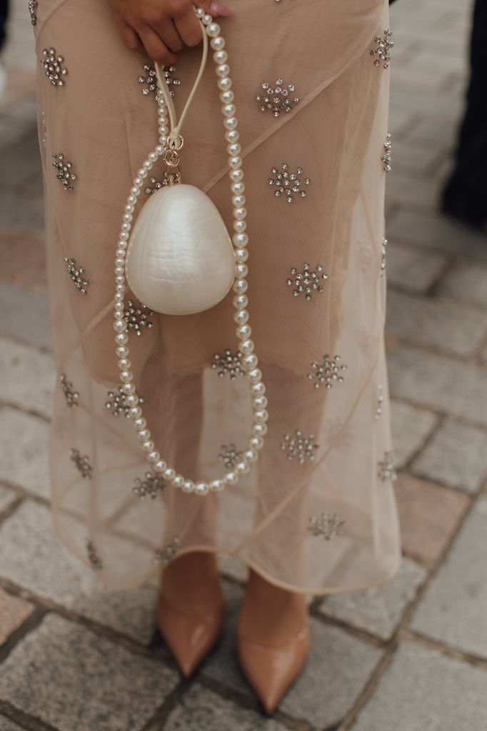 Invitada con bolso en forma de perla y cadena de perlas