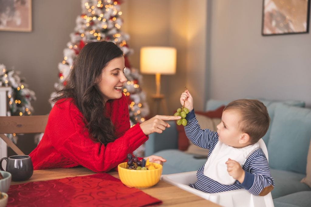 madre con su hijo pequeño con un racimo de uvas, en Navidad