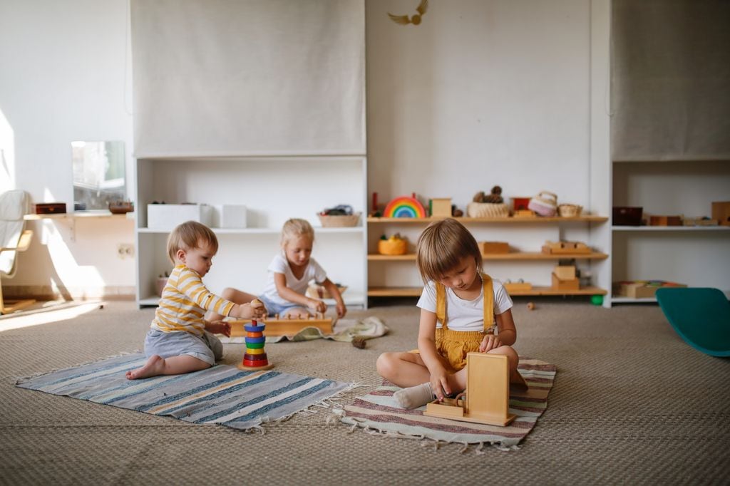Niños jugando en el suelo con juguetes de madera en la guardería