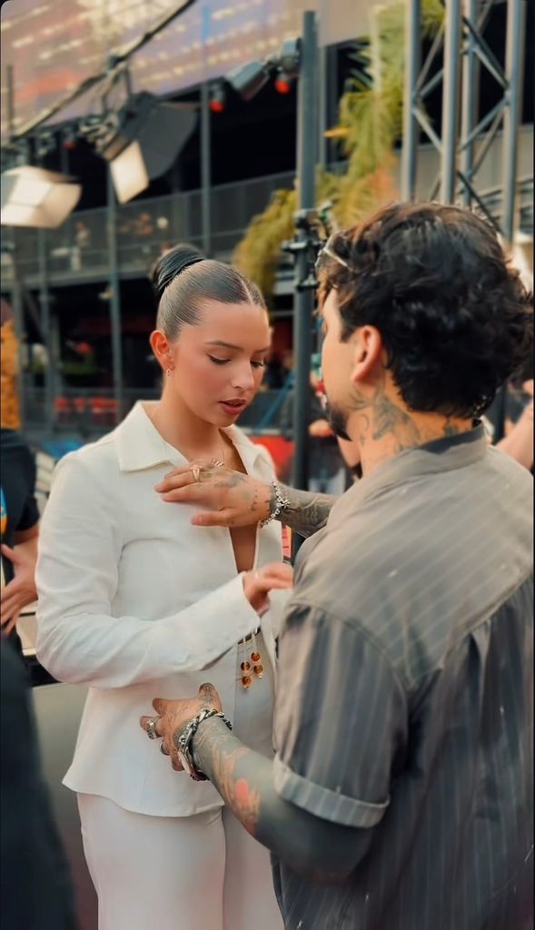 Ángela Aguilar y Christian Nodal persignándose antes de salir al escenario.