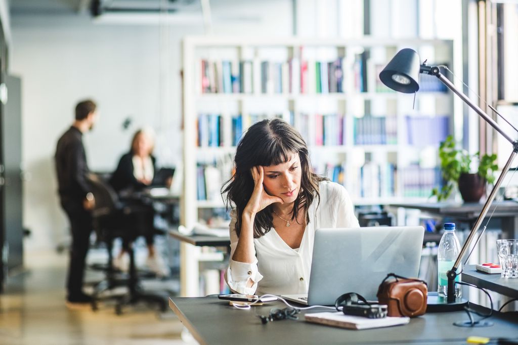 mujer preocupada en la oficina, mirando su ordenador portátil