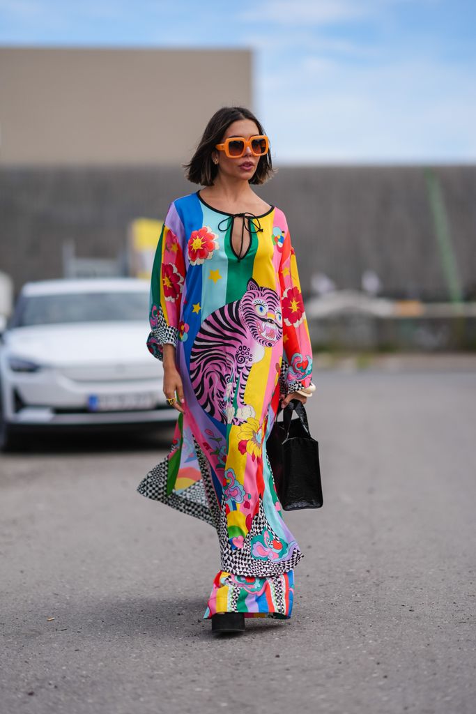 COPENHAGEN, DENMARK - AUGUST 5: A guest wears orange sunglasses, silver earrings, bright multi-colored Manoush crazy tiger long sleeve dress, bright multi-colored Manoush crazy tiger pants, black platform shoes, black leather bag, gold rings, outside Rolf Ekroth, during the Copenhagen Fashion Week Spring/Summer 2024-2025 on August 5, 2024 in Copenhagen, Denmark. (Photo by Edward Berthelot/Getty Images)