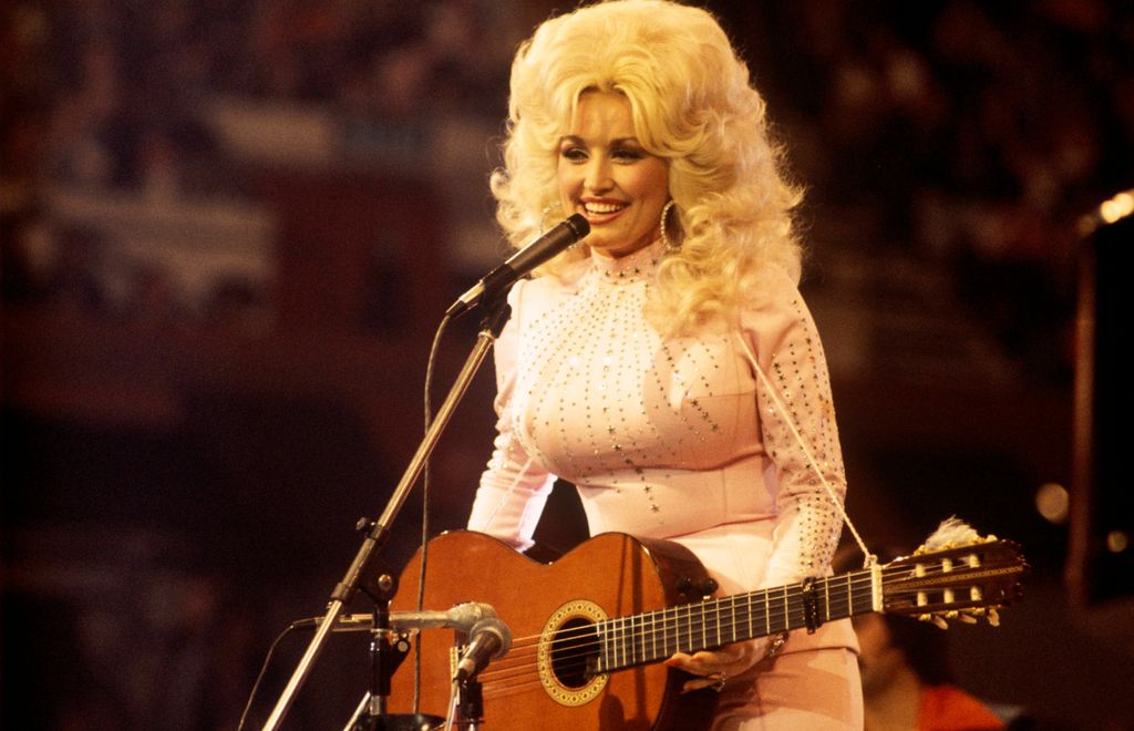 American singer, songwriter and actress Dolly Parton, performs with a guitar, 1976