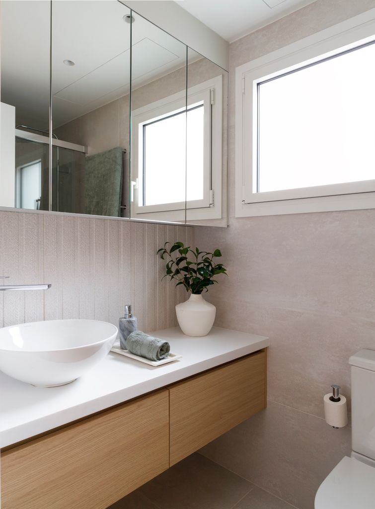 Baño moderno con ventana y espejo tipo camerino.