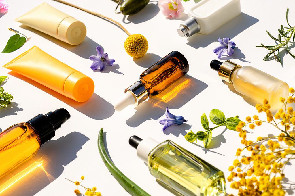 Bodegón de cremas y sérums sobre fondo con plantas y flores