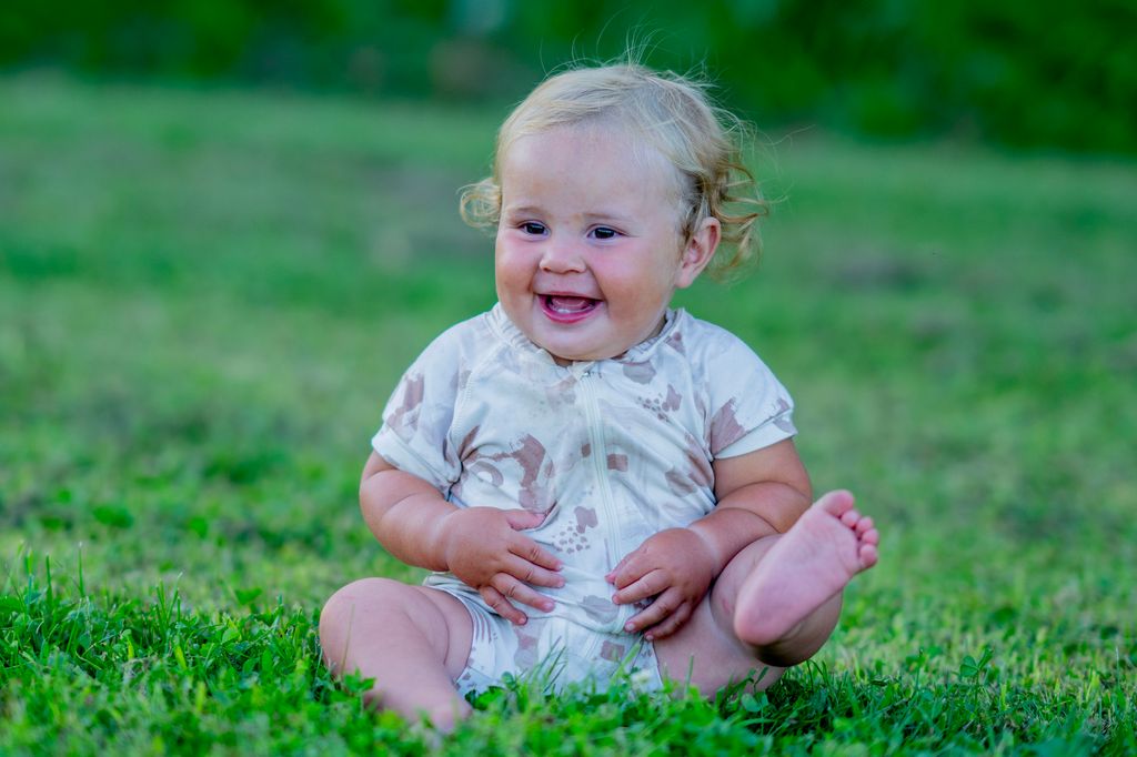 Bebé sentada feliz descalza en el campo