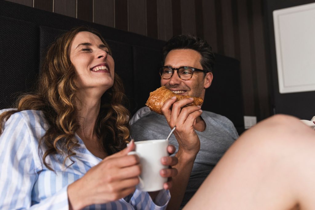 Pareja en la cama feliz tomando un desayuno