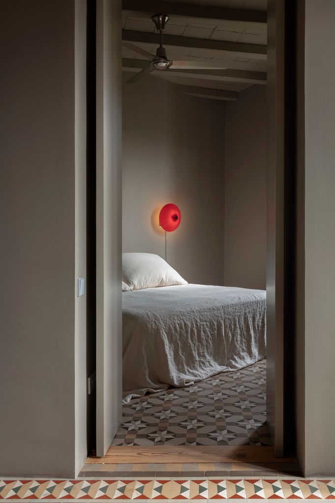 Una vivienda reformada y puesta al día de la que vemos el dormitorio que conserva los suelos con una rica gráfica