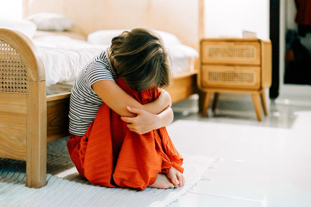 Niño con miedo sentado en su dormitorio