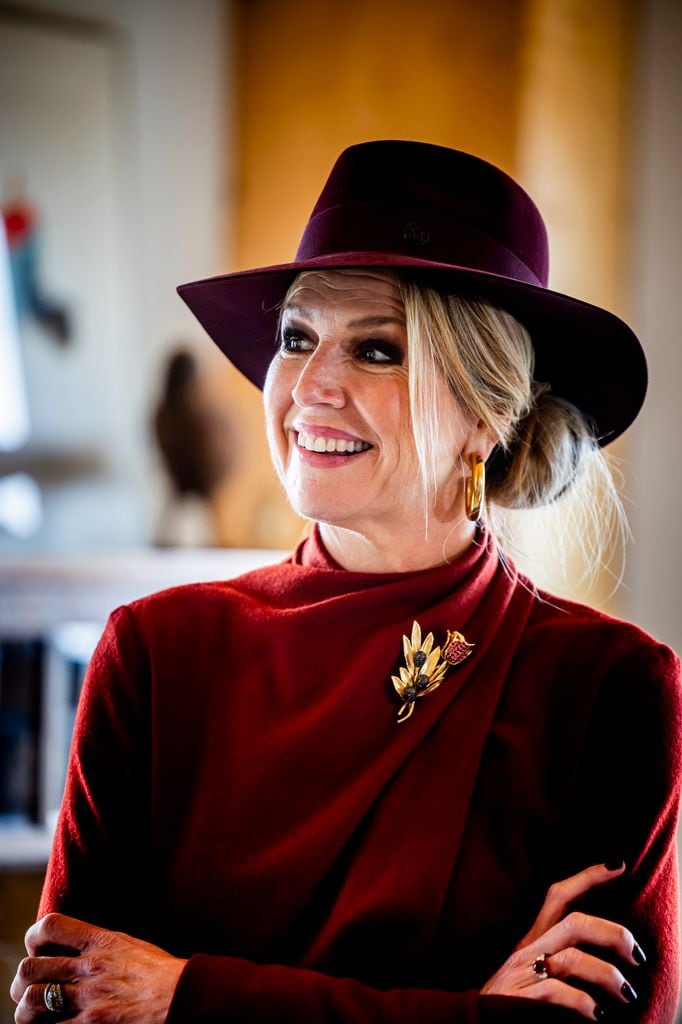 La reina Máxima de Holanda agrega un broche con su vestido burgundy.