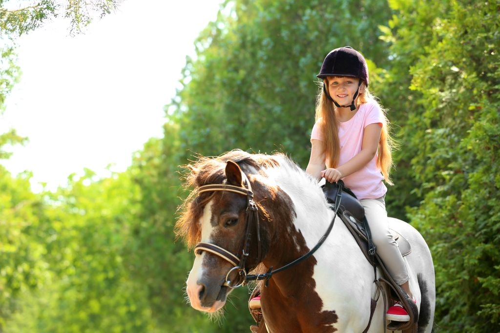 Niña en curso de equitación en campamento de verano