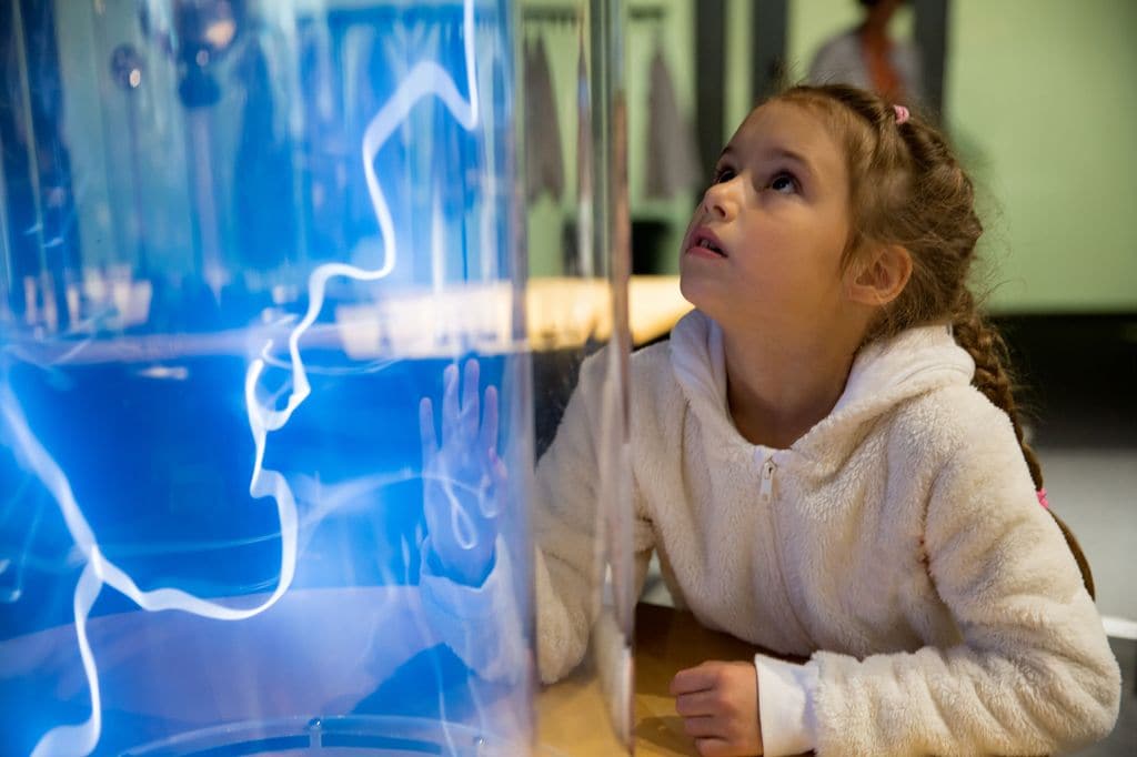 Niña mirando un experimento en un museo