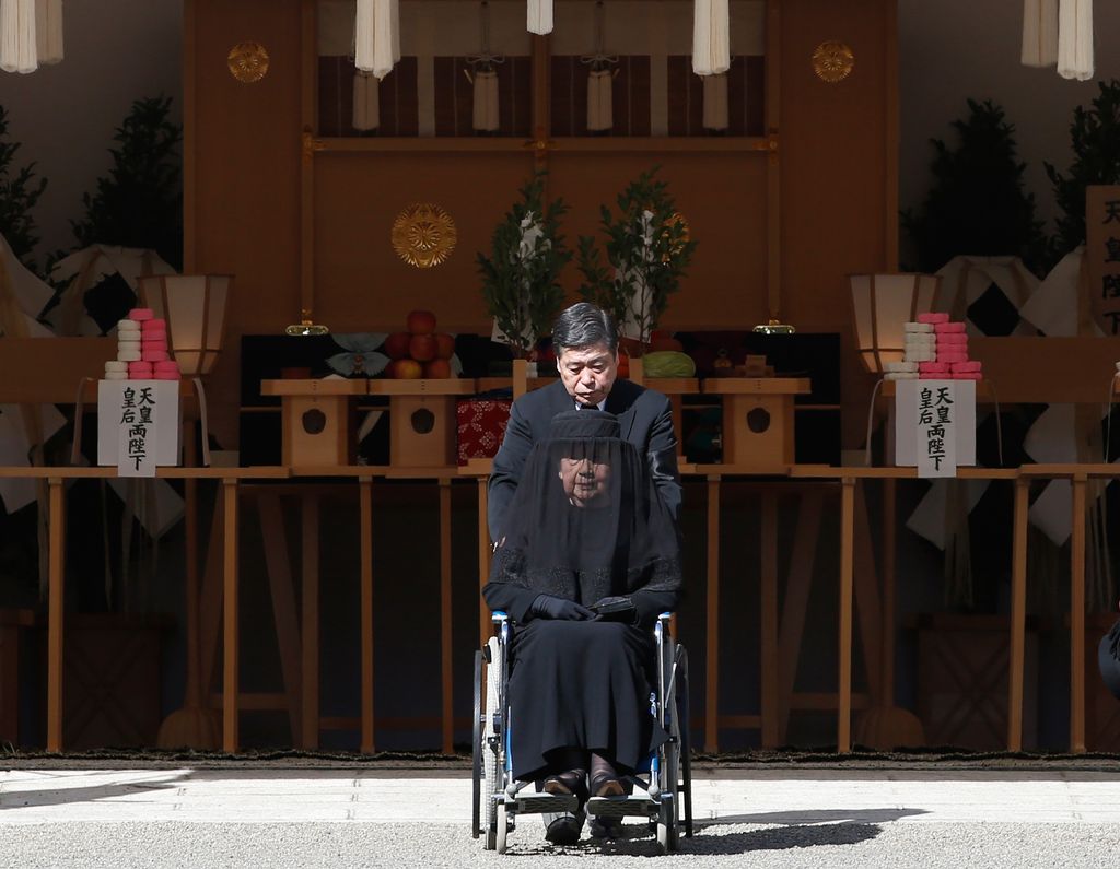 Plano medio de Yuriko de Japón siendo trasladada en silla de ruedas tras un funeral