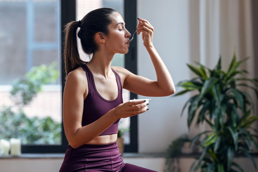 mujer con ropa deportiva comiendo un yogur