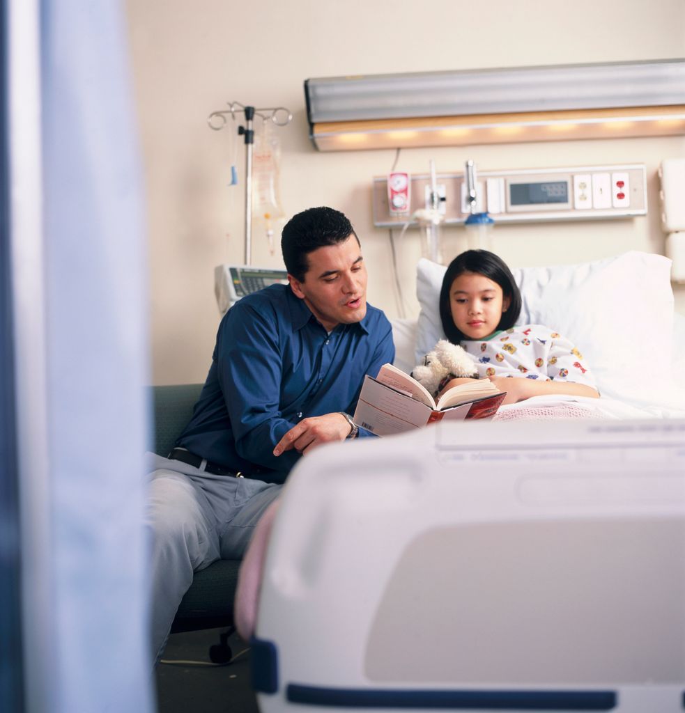 Padre leyéndole a su hija un libro en el hospital