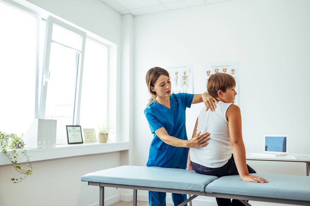 niño en una consulta de fisioterapia revisando su espalda