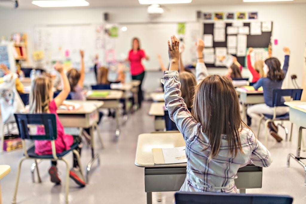 Niños en clase levantando la mano