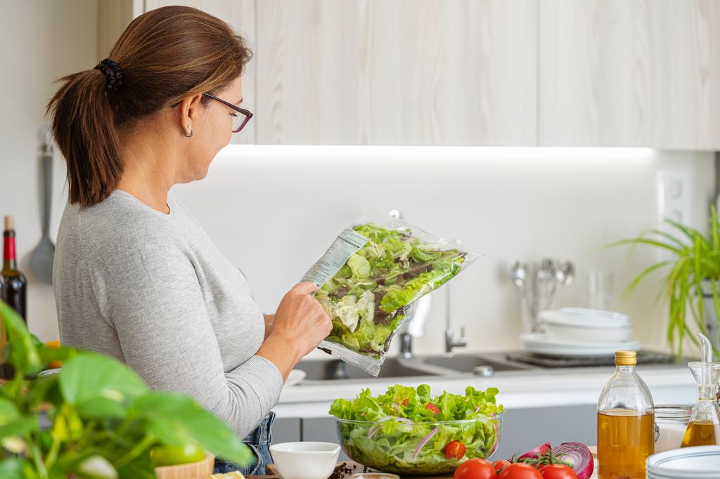 mujer mirando una bolsa de ensalada lista para consumir