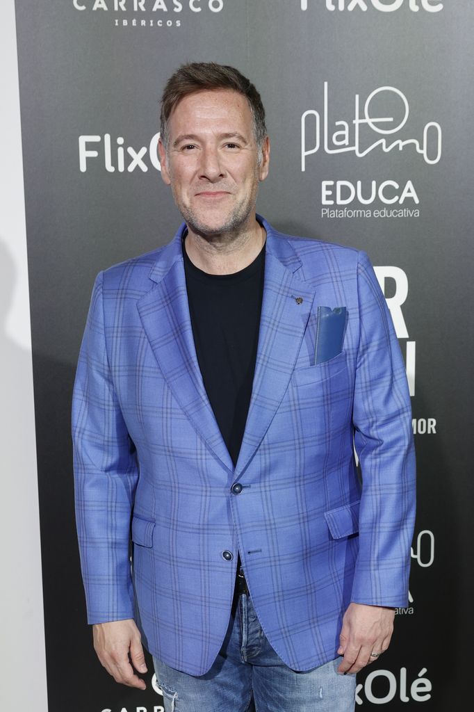 Carlos Latre posa con traje azul claro y camisa negra en evento.