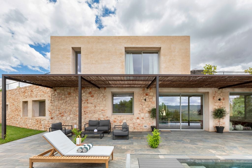 Fachada de una casa de campo de piedra, con piscina, muebles de exterior