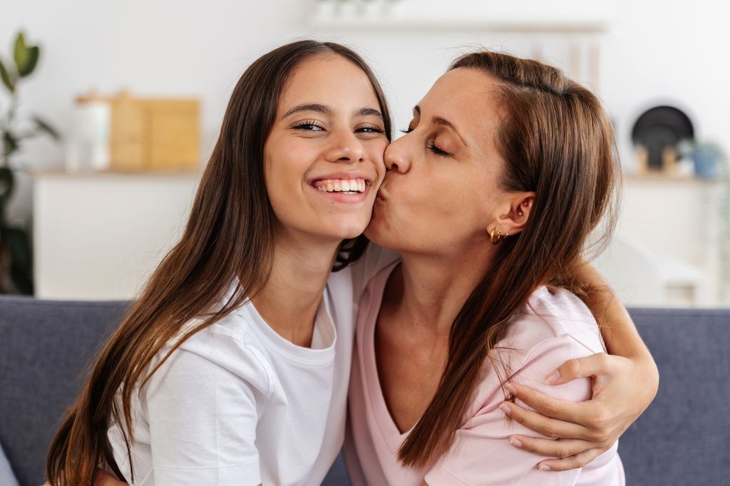 madre dándole un beso a su hija adolescente