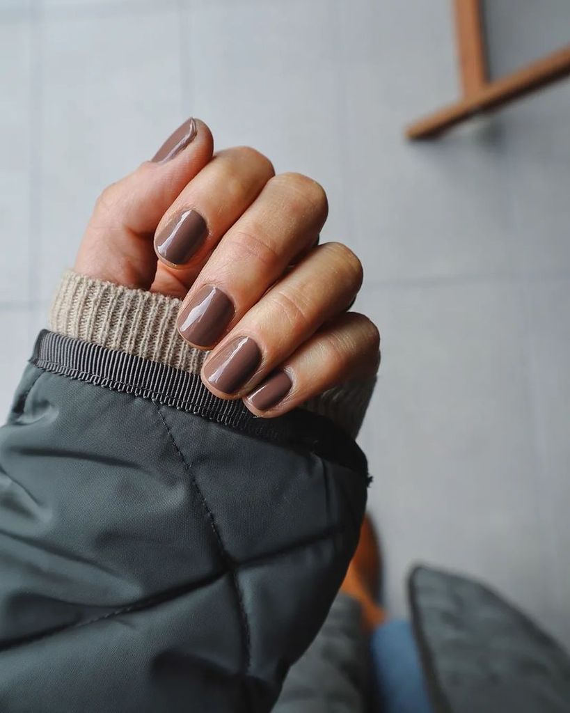 Manicura mole brown en uñas cortas con acabado brillante, en look invernal.