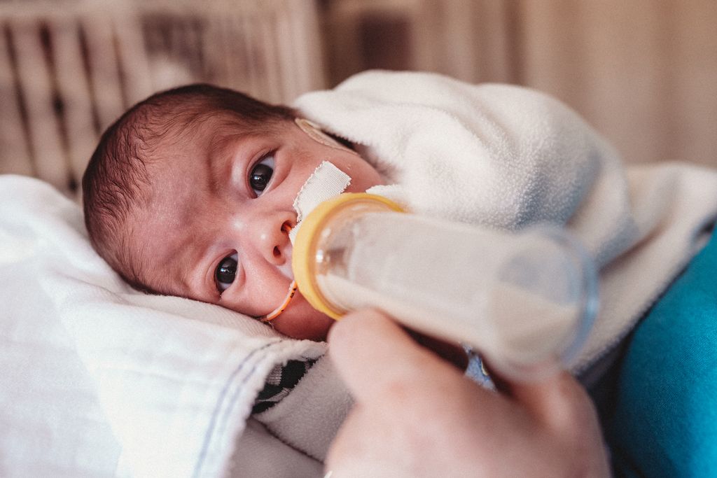 Bebé prematuro ingresado en hospital tomando biberón