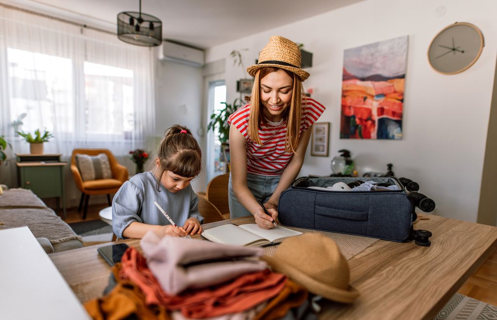 madre y su hija haciendo una lista mientras preparan la maleta