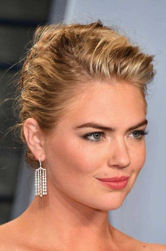 Kate Upton close up con cabello recogido con un moño y vestido strapless