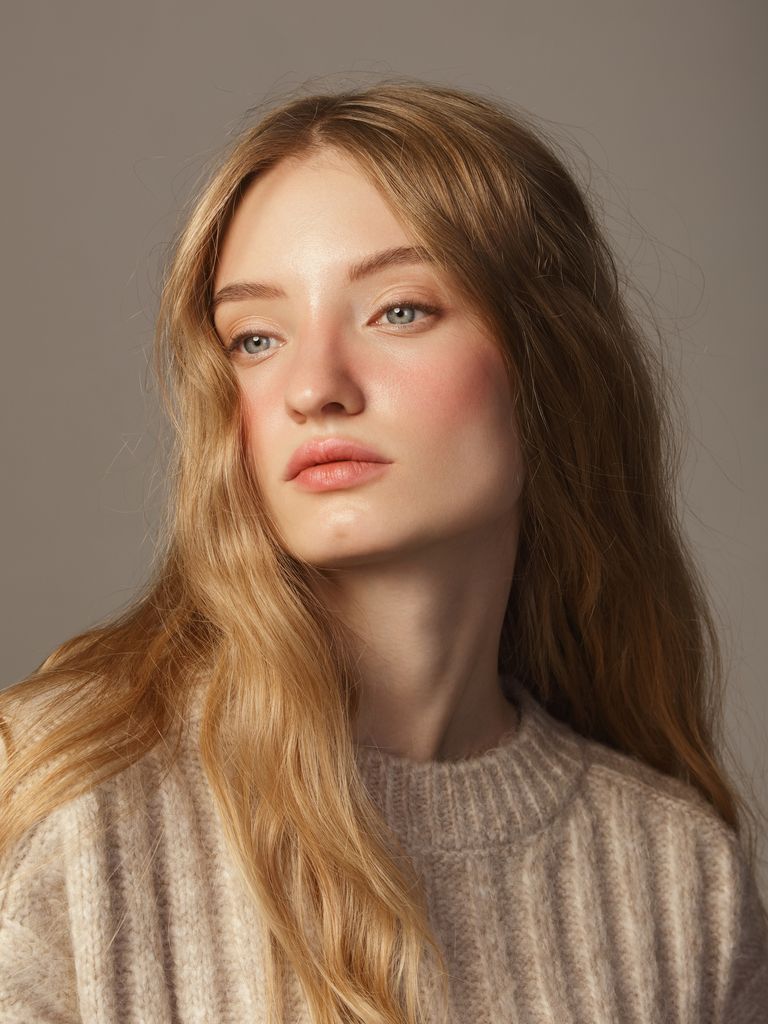 Retrato de chica con el pelo largo y ondulado con jersey beige