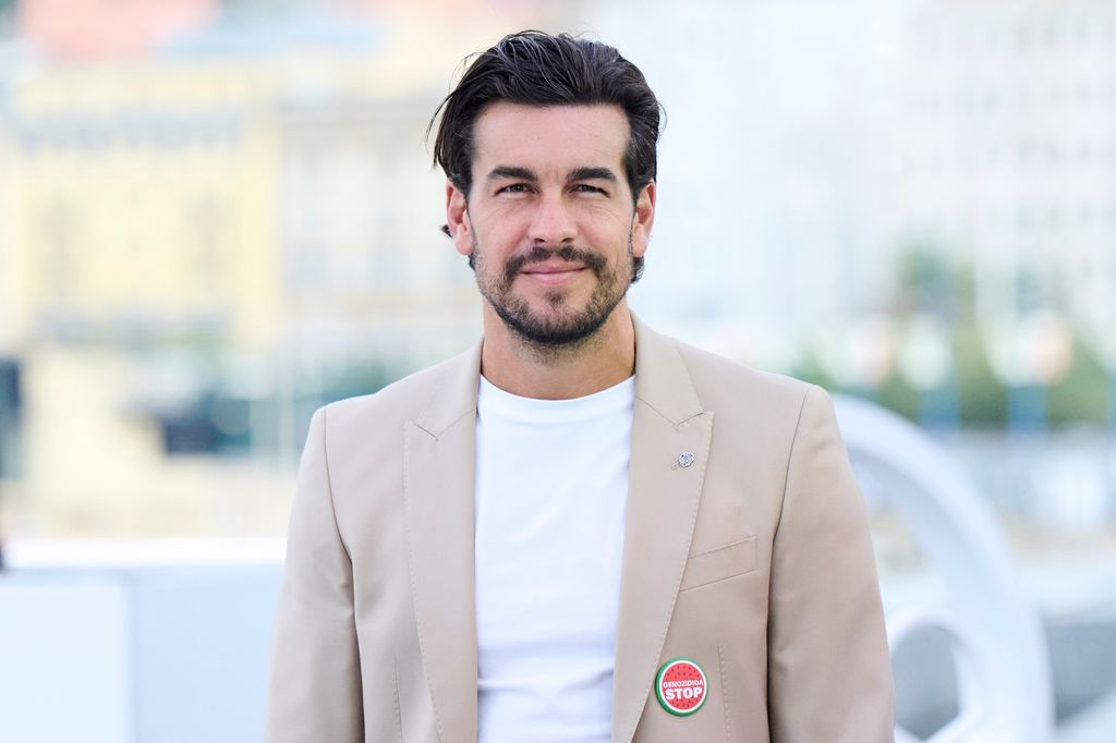 Mario Casas posa durante el Festival de San Sebastián con un traje crudo y una camiseta blanca. Luce pelo larguito y barba