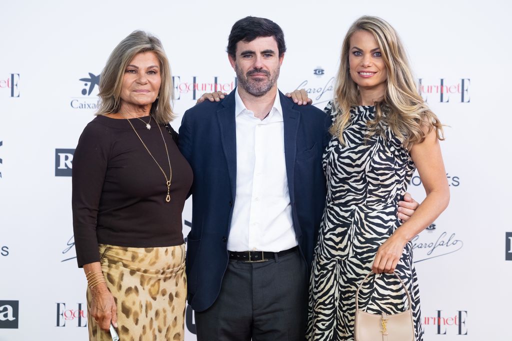Tres personas en un evento, dos mujeres y un hombre, posando para una foto.