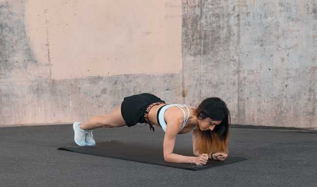Mujer realizando ejercicio de plancha con antebrazos apoyados en el suelo