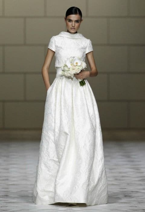 Una manera de decidirse por dos vestidos de novia que parecen perfectos puede ser el que tenga el tejido menos 'rebelde': más resistente a las arruguitas y fácil de transportar. En la imagen, Pronovias, colección de novia 2015.
