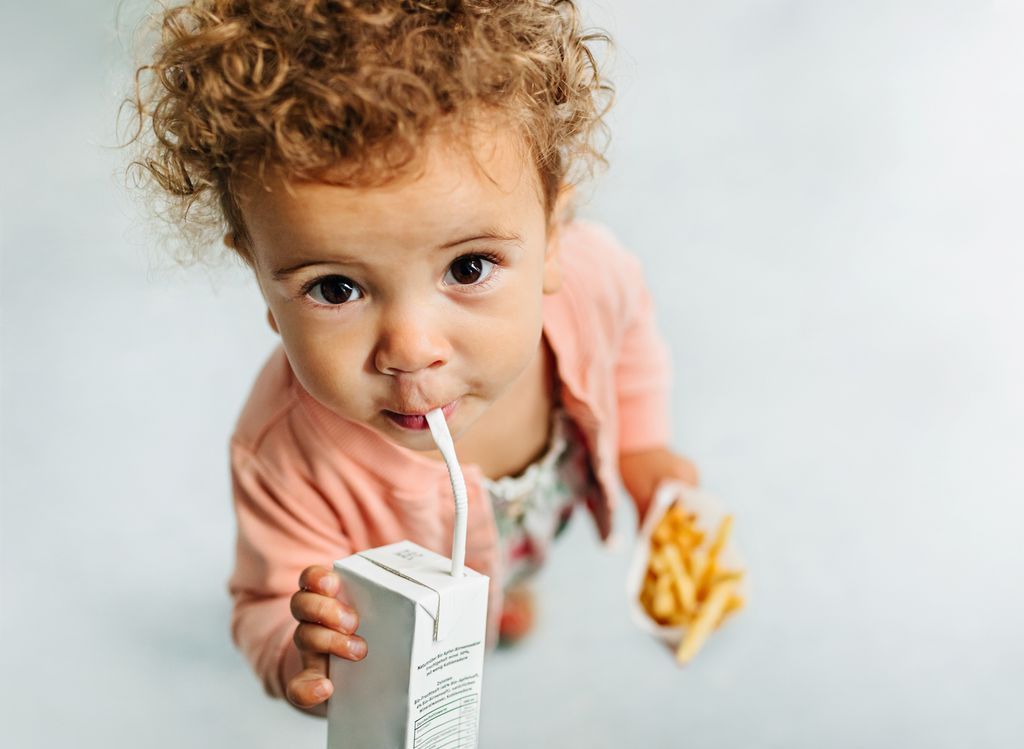 Niño pequeño con brick de leche y patatas fritas